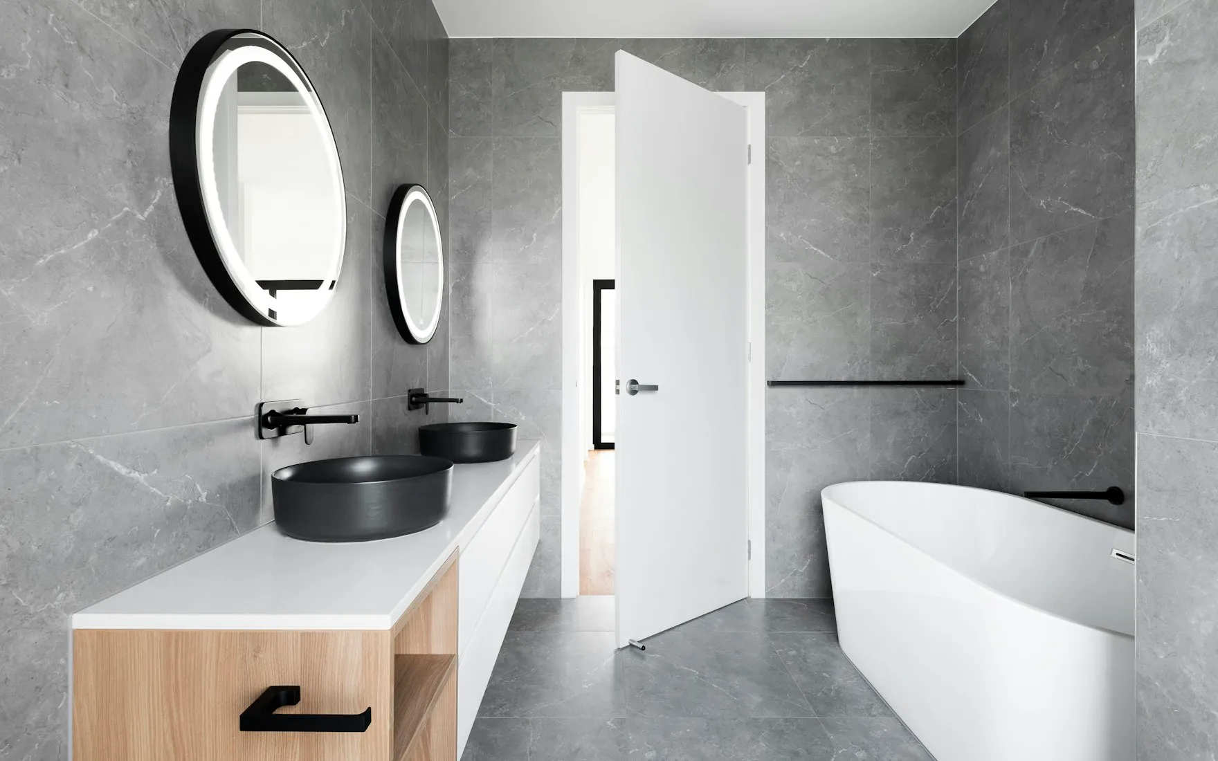 Salle de bain avec vasque en marbre, carrelage sombre et menuiserie noire