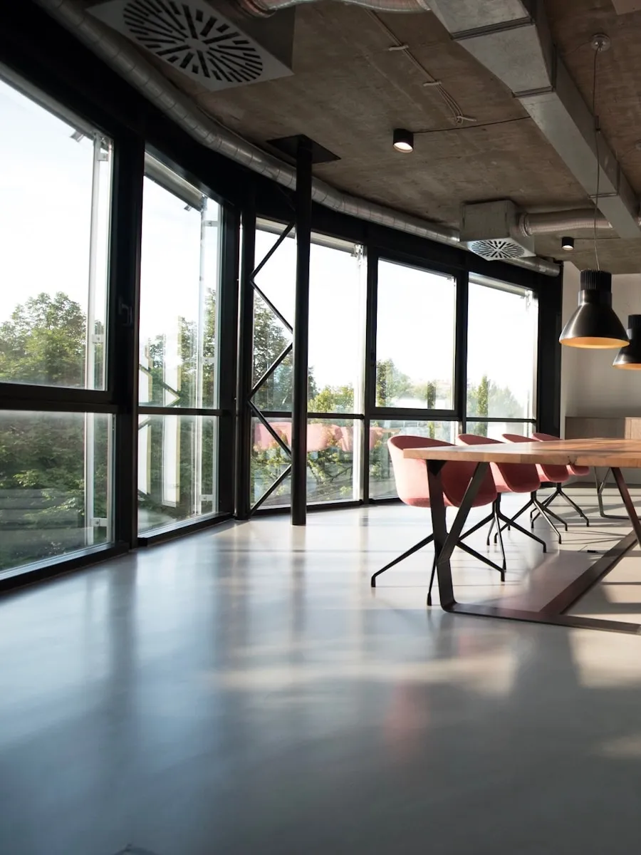 Espace industriel avec verrière en acier noir, béton et suspensions métalliques