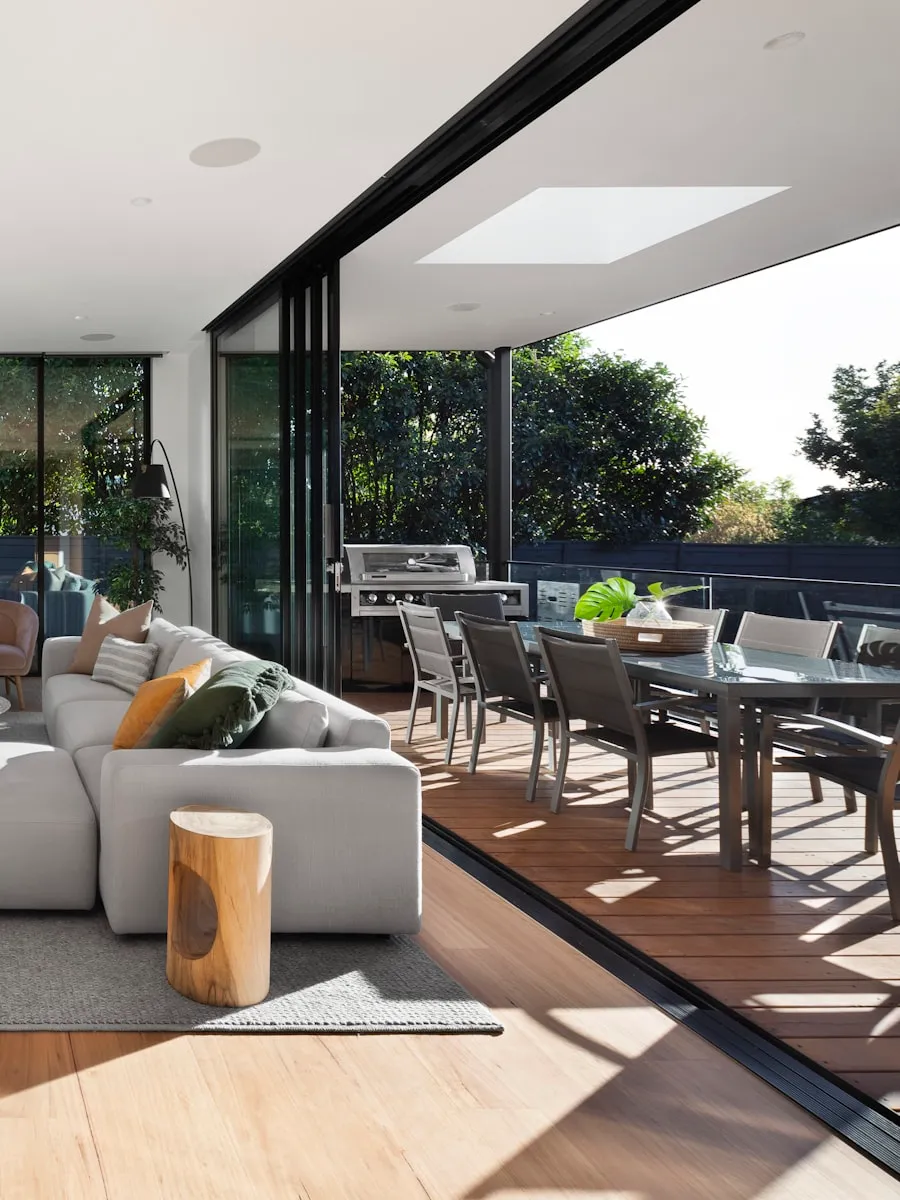 Salon moderne avec baies vitrées, mobilier gris et panneau de bois