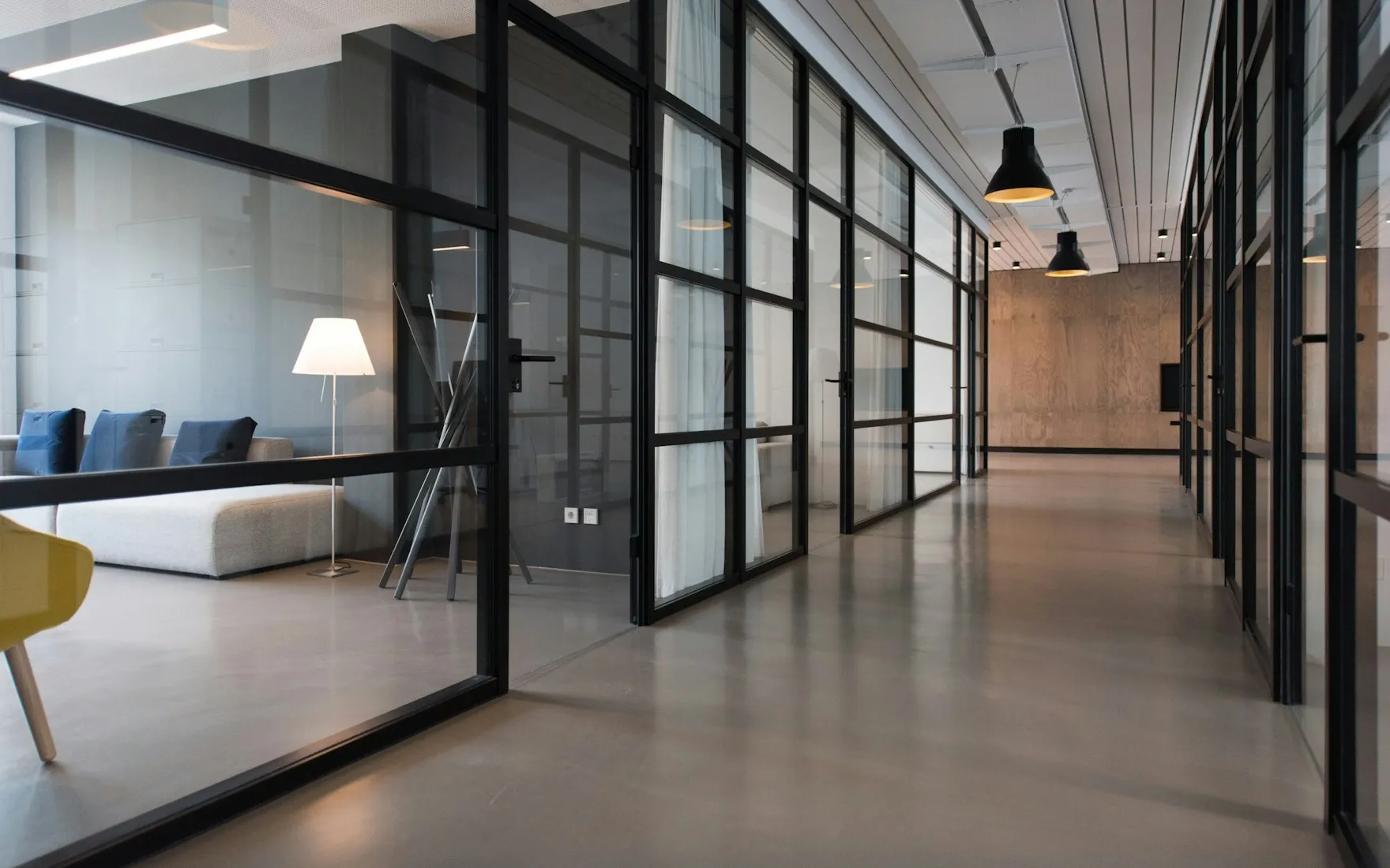 Espace industriel avec verrière en acier noir, béton et suspensions métalliques