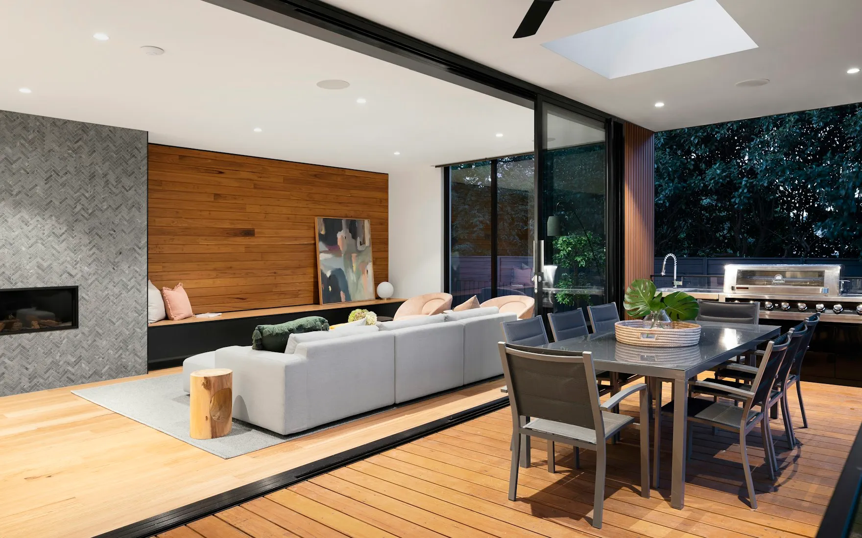 Salon moderne avec baies vitrées, mobilier gris et panneau de bois